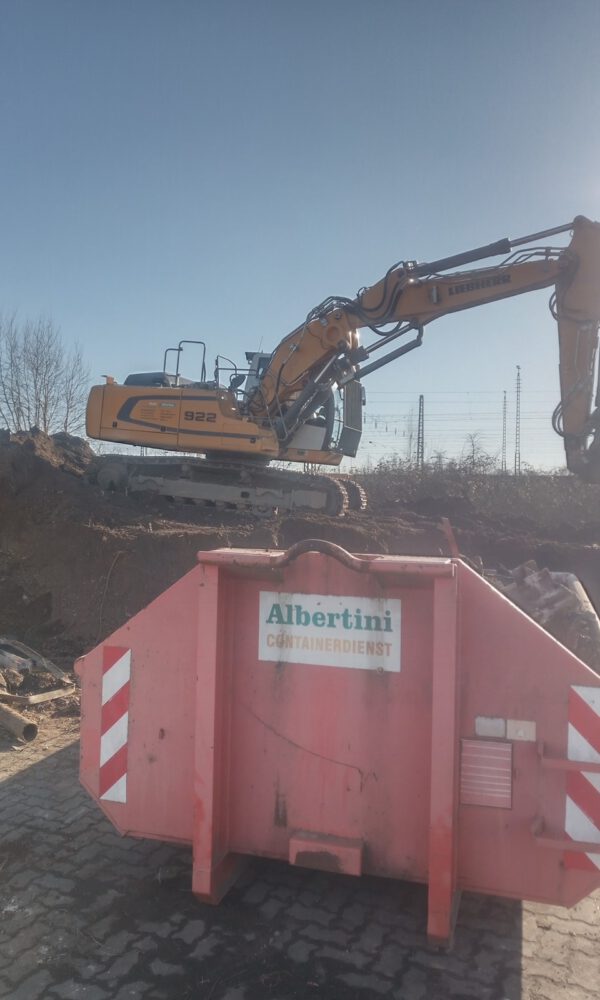 Ein Bagger belädt einen Container der Firma Albertini mit Erde
