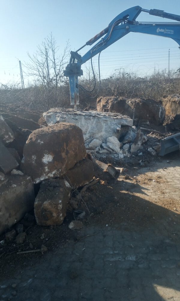 Ein Baufahrzeug mit Meißel zerkleinert einen Betonblock