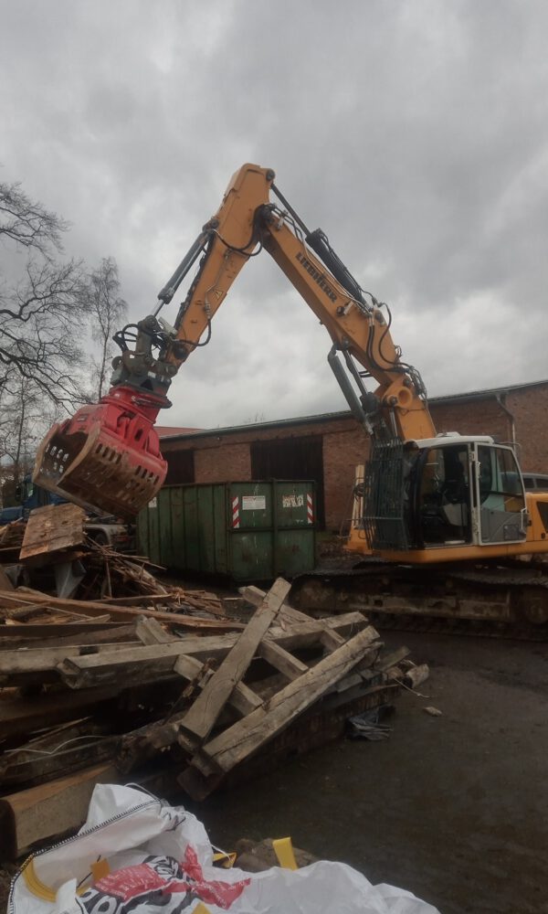 Ein Bagger steht neben einem Haufen Altholz