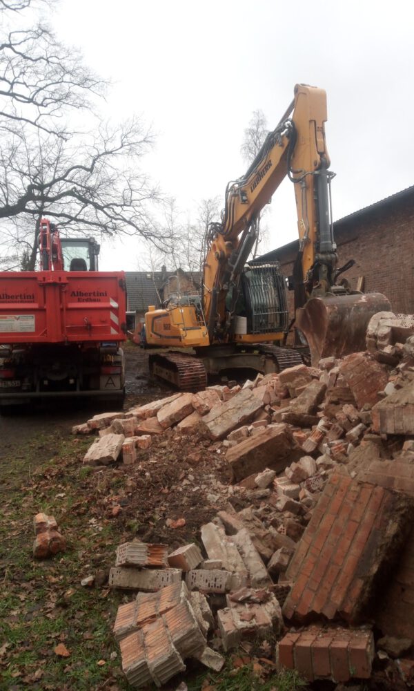 Ein Bagger und ein LKW stehen vor einem Haufen mit Bauschutt