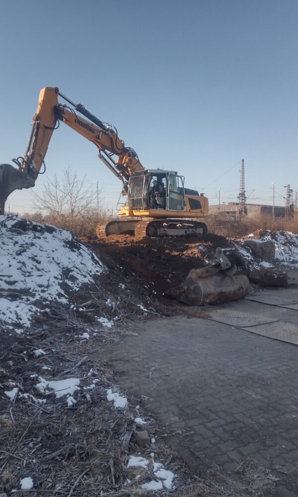 Ein Bagger arbeitet an einem schneebedeckten Haufen