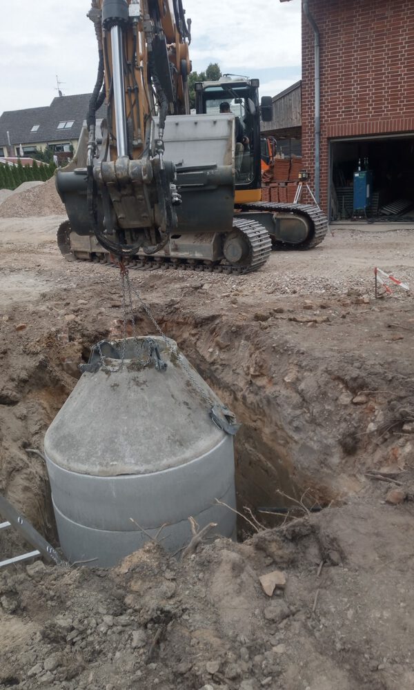 Ein Bagger setzt ein Element auf einen Schacht in der Erde