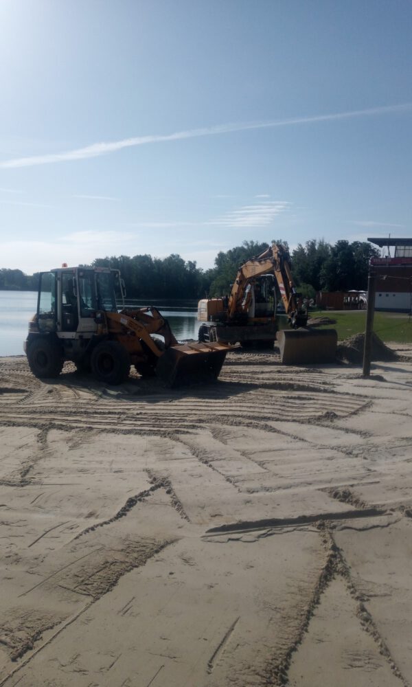 Zwei Bagger arbeiten an einem kleinen Strand am See