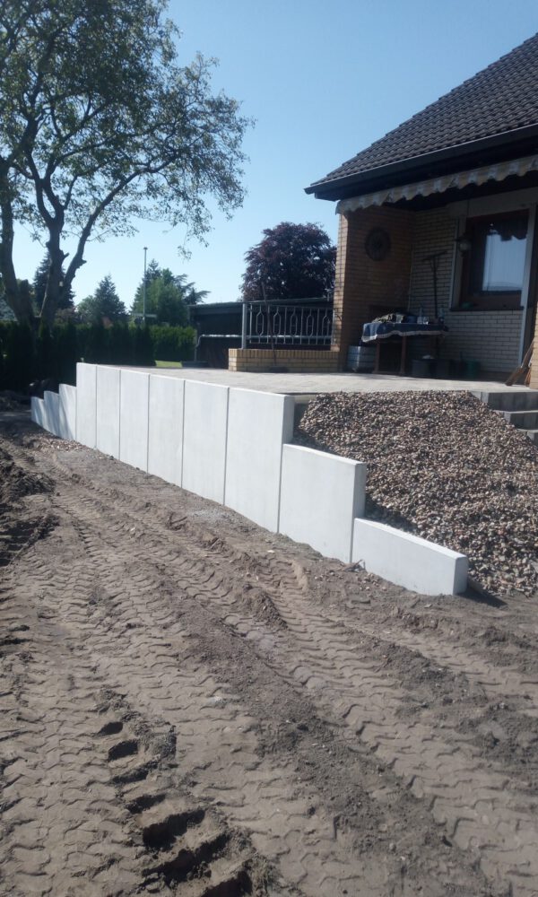 Ein Haus mit einer Terrasse. die mit hohen Steinen eingefasst wurde