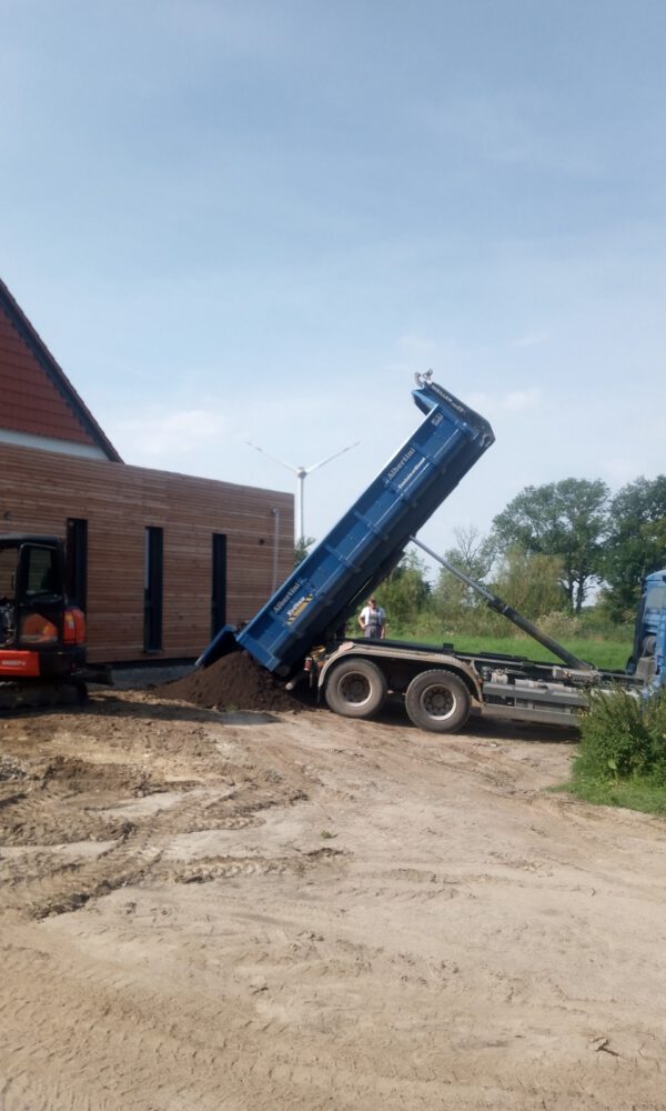 Ein blauer LKW kippt Erde auf einer Baustelle ab
